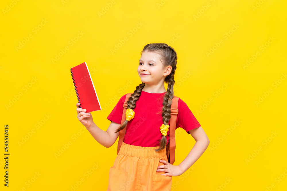 A schoolgirl with a satchel is getting ready to go to school. Children's education. Preparatory courses for schoolchildren. Additional classes for successful exams. Yellow isolated background. A schoolgirl with a satchel is getting ready to go to school. Children's education. Preparatory courses for schoolchildren. Additional classes for successful exams. Yellow isolated background.