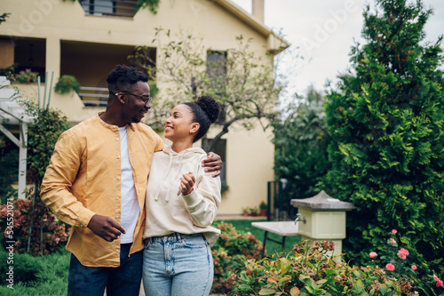 Multiracial couple holding keys and standing outside their new home