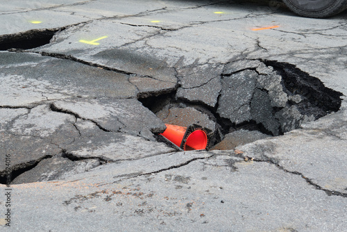 Sink hole in middle of asphalt street following collapse of road