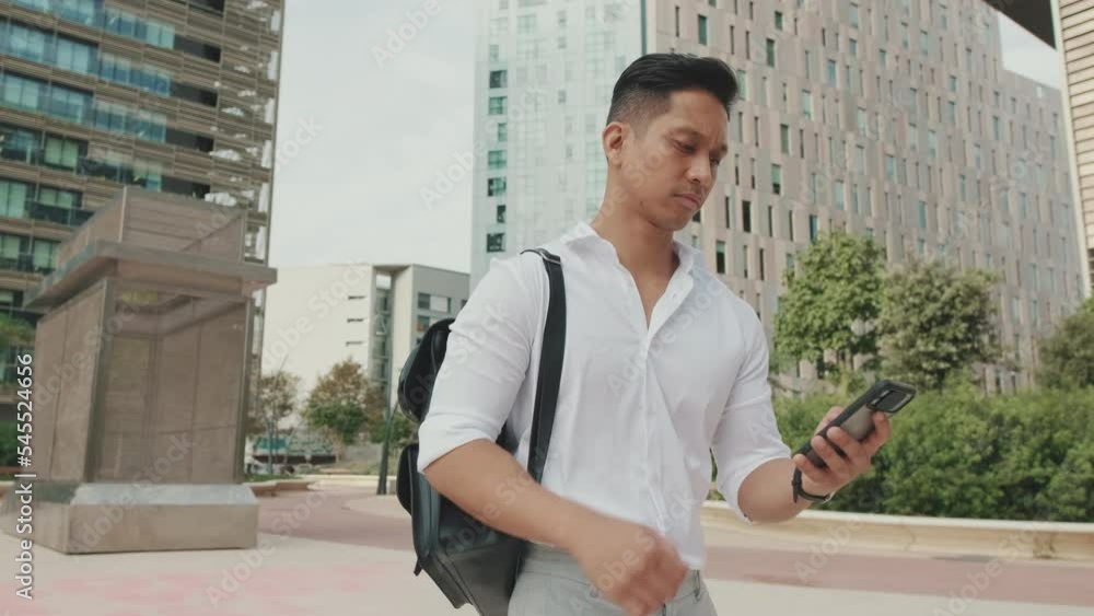 Young businessman with mobile phone in his hands walks past the business center Young businessman with mobile phone in his hands walks past the business center