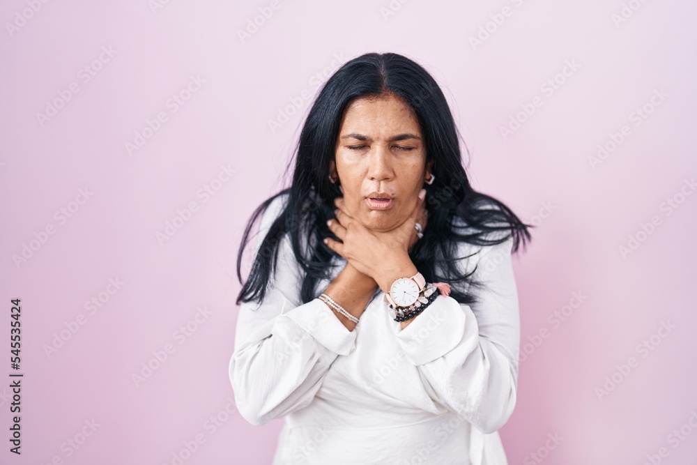 Mature hispanic woman standing over pink background shouting suffocate because painful strangle. health problem. asphyxiate and suicide concept. Mature hispanic woman standing over pink background shouting suffocate because painful strangle. health problem. asphyxiate and suicide concept.