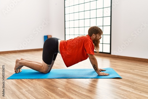 Young redhead man stretching at sport center