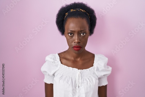 African woman with curly hair standing over pink background skeptic and nervous, frowning upset because of problem. negative person.