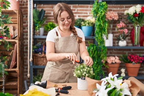 Young blonde woman florist cutting plants at florist