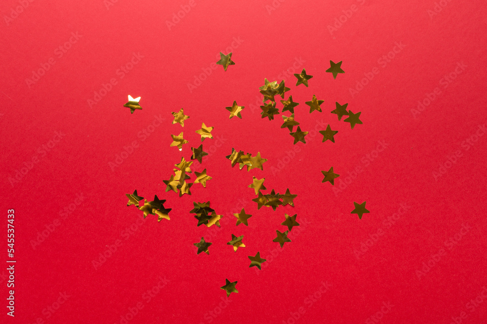 Golden confetti stars on color background, top view Golden confetti stars on color background, top view
