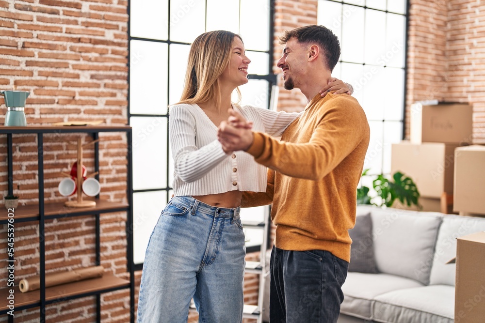 Young man and woman couple smiling confident dancing at new home
