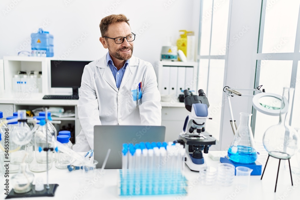 Middle age hispanic man wearing scientist uniform working at laboratory Middle age hispanic man wearing scientist uniform working at laboratory