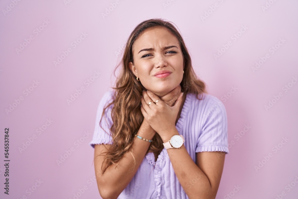 Young hispanic woman standing over pink background shouting suffocate because painful strangle. health problem. asphyxiate and suicide concept. Young hispanic woman standing over pink background shouting suffocate because painful strangle. health problem. asphyxiate and suicide concept.