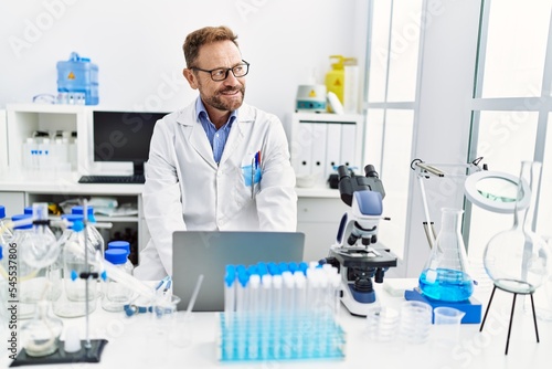 Middle age hispanic man wearing scientist uniform working at laboratory