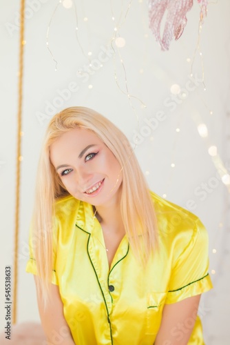 blonde woman in yellow pajams in christmas decor bed photo