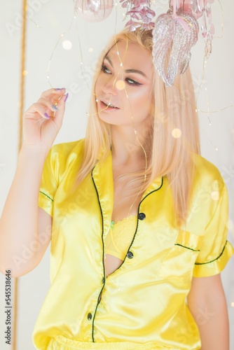 blonde woman in yellow pajams in christmas decor bed photo