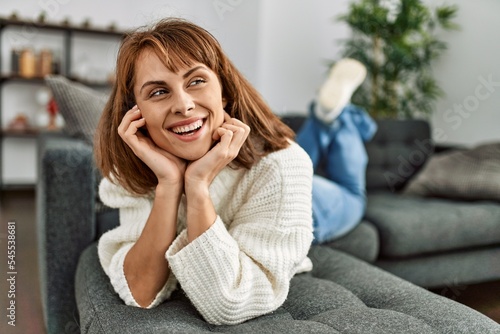 Young caucasian woman smiling confident lying on sofa at home © Krakenimages.com