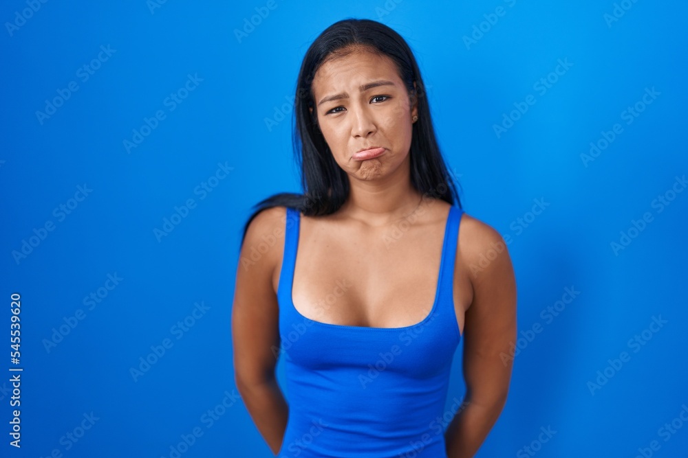 Hispanic woman standing over blue background depressed and worry for distress, crying angry and afraid. sad expression. Hispanic woman standing over blue background depressed and worry for distress, crying angry and afraid. sad expression.
