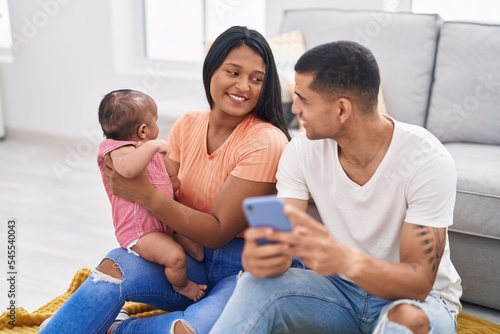 Hispanic family using smartphone sitting on floor at home