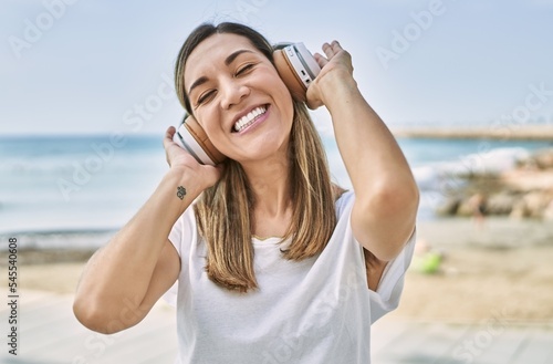 Young hispanic woman smiling confident listening to music at seaside