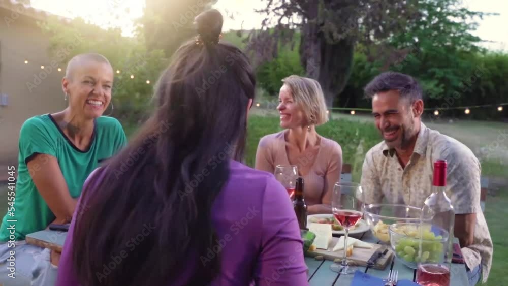 Happy friends laughing with big smile around the table in a summer diner. Smiling people eating at house patio. Smiles, cheerfulness concept. Happy friends laughing with big smile around the table in a summer diner. Smiling people eating at house patio. Smiles, cheerfulness concept.