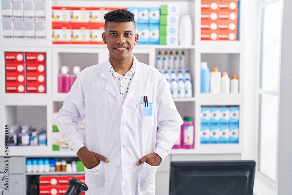 Young latin man pharmacist smiling confident standing at pharmacy
