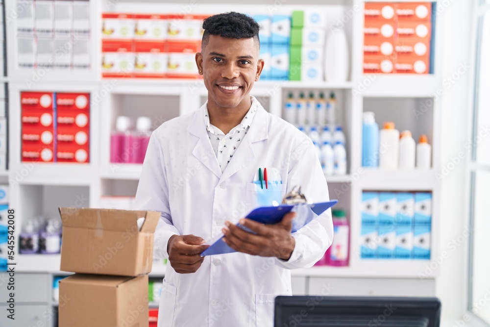 Young latin man pharmacist reading report at pharmacy