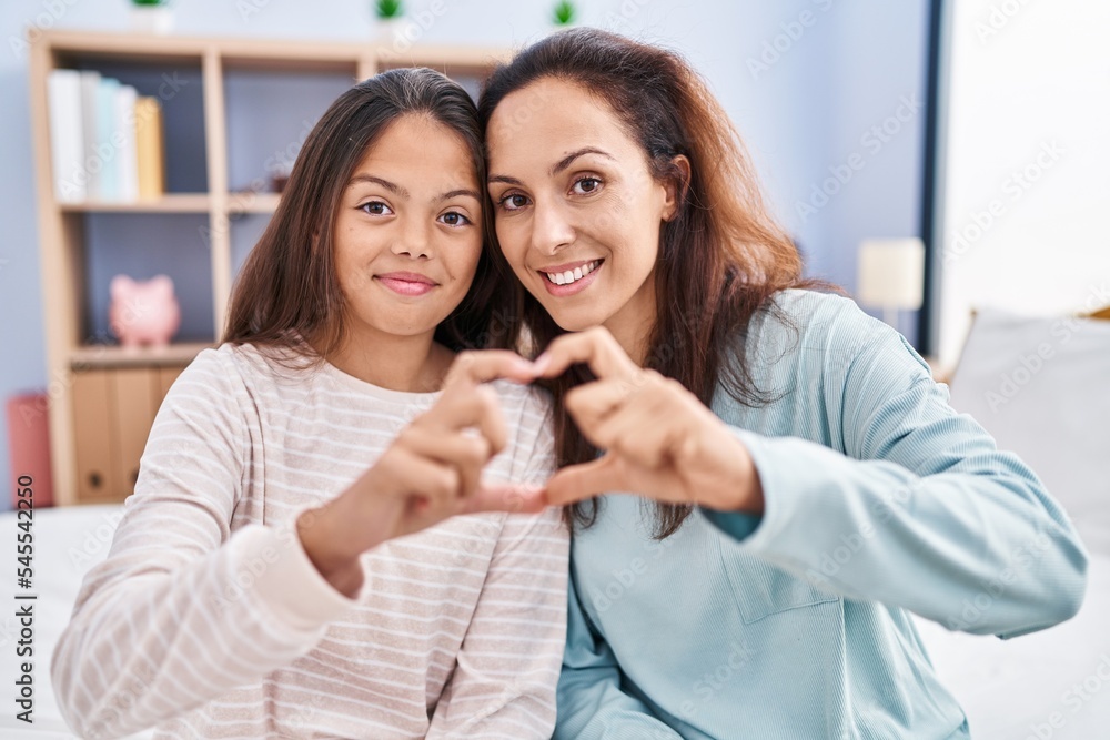 Woman and girl mother and daughter doing heart gesture with hands at bedroom Woman and girl mother and daughter doing heart gesture with hands at bedroom