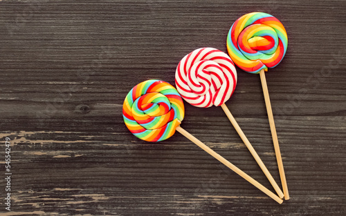 Three colorful lollipops on a wooden background