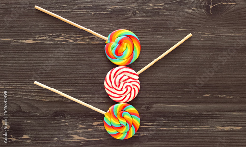 Three multicolored lollipops on a wooden background