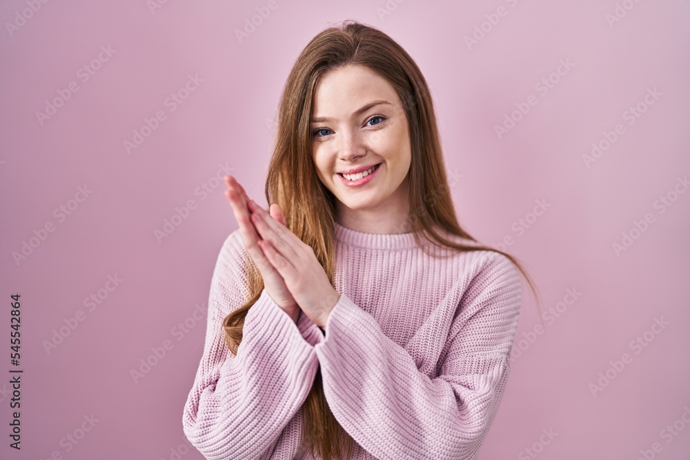 Young caucasian woman standing over pink background clapping and applauding happy and joyful, smiling proud hands together Young caucasian woman standing over pink background clapping and applauding happy and joyful, smiling proud hands together