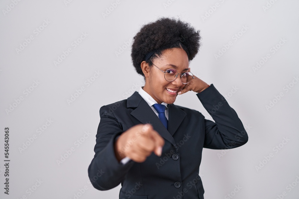 Beautiful african woman with curly hair wearing business jacket and glasses smiling doing talking on the telephone gesture and pointing to you. call me. Beautiful african woman with curly hair wearing business jacket and glasses smiling doing talking on the telephone gesture and pointing to you. call me.