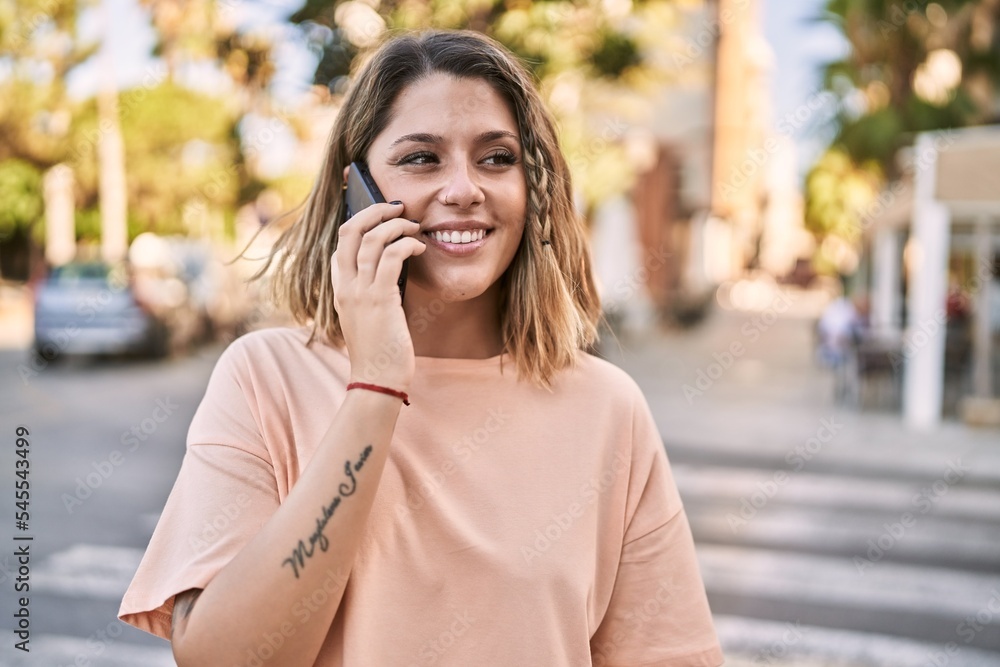 Young hispanic woman smiling confident talking on the smartphone at street