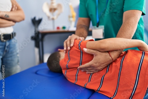 Family having physiotherapy session massaging child back at rehab clinic