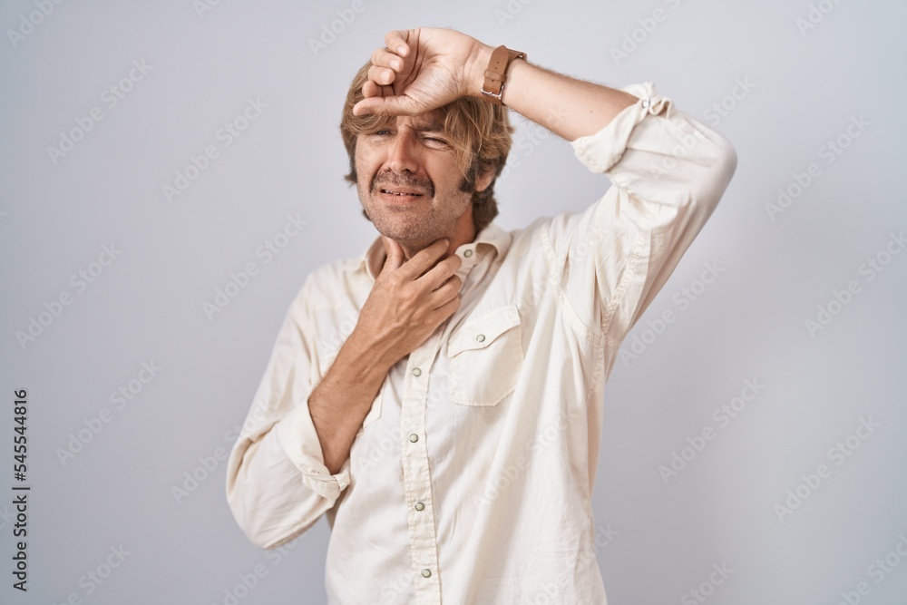 Middle age man standing over isolated background touching forehead for illness and fever, flu and cold, virus sick Middle age man standing over isolated background touching forehead for illness and fever, flu and cold, virus sick