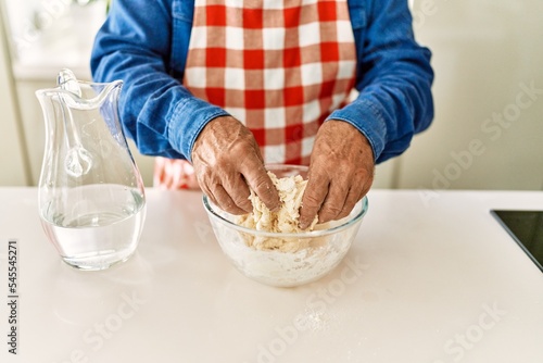 Senior man cooking dough at kitchen