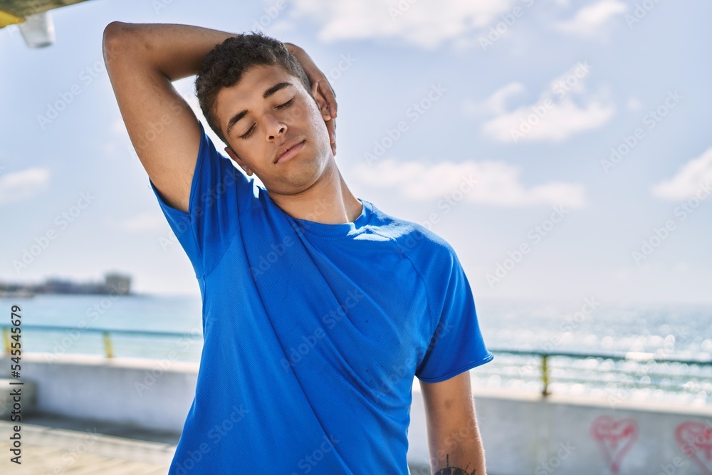 Young hispanic man stretching neck muscles outdoors Young hispanic man stretching neck muscles outdoors