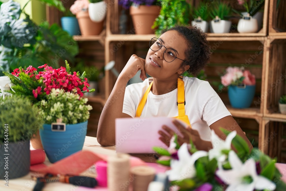 African american woman florist smiling confident reading document at flower shop
