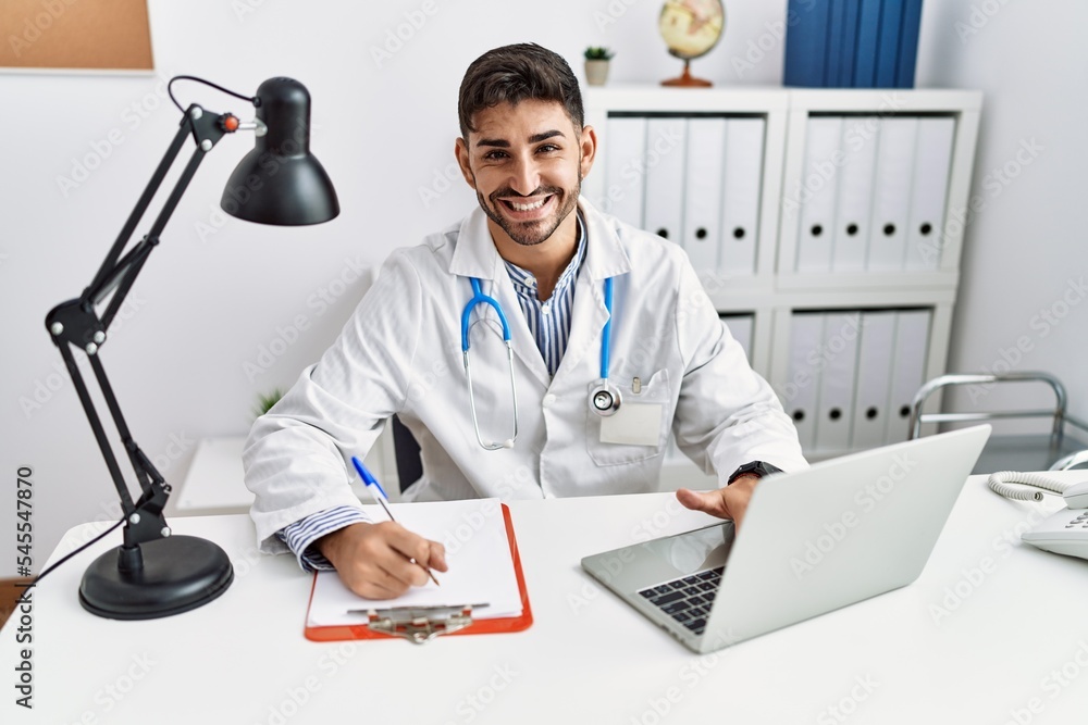 Fototapeta premium Handsome hispanic man working as doctor at medical consultation