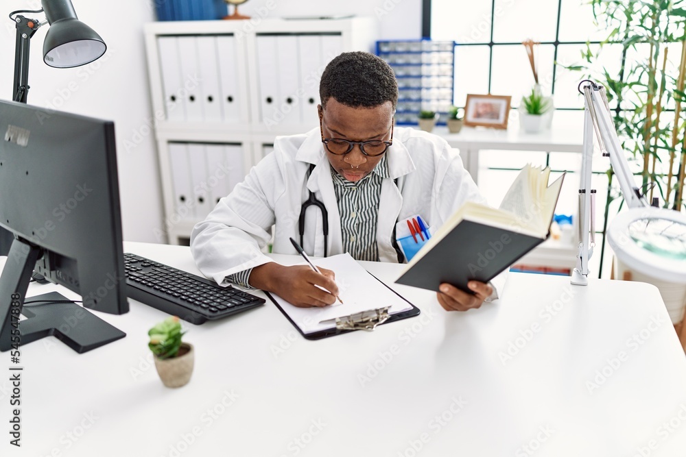 Young african man working as doctor writing notes at medical clinic Young african man working as doctor writing notes at medical clinic