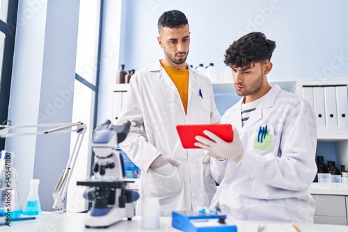 Two man scientists using touchpad working at laboratory