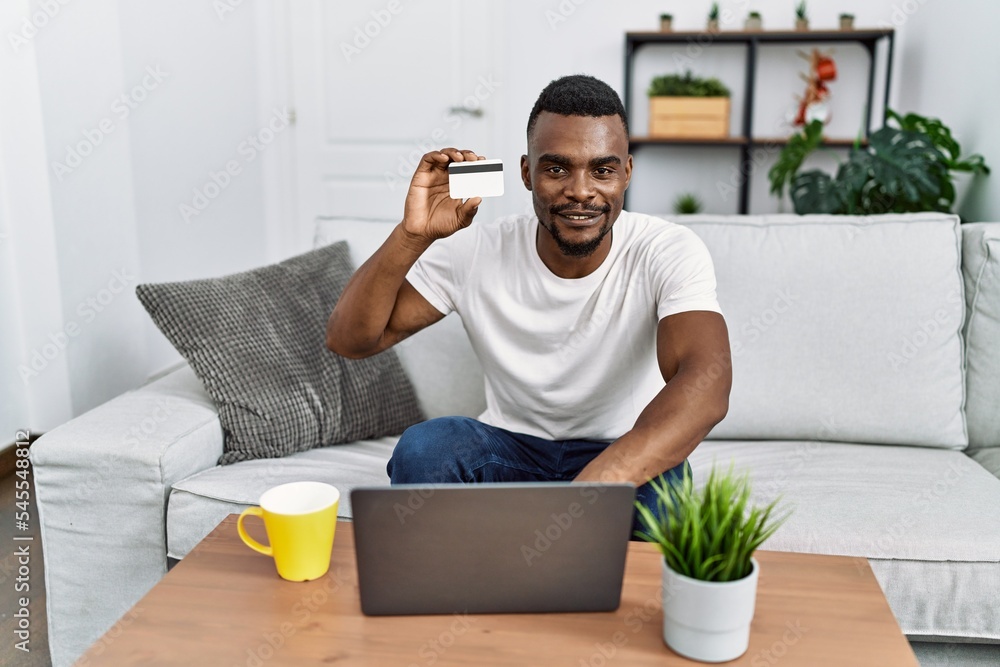 Young african american man using laptop and credit card at home Young african american man using laptop and credit card at home