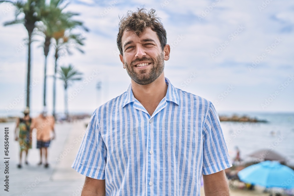 Young hispanic man smiling happy standing at the beach. Young hispanic man smiling happy standing at the beach.