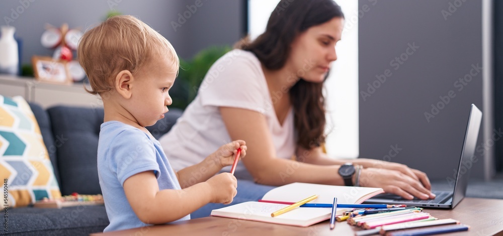 Fototapeta premium Mother and son drawing on notebook using laptop at home