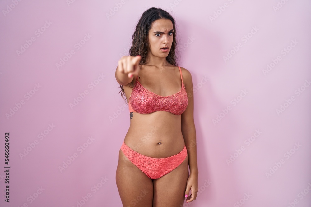 Fototapeta premium Young hispanic woman wearing lingerie over pink background pointing displeased and frustrated to the camera, angry and furious with you