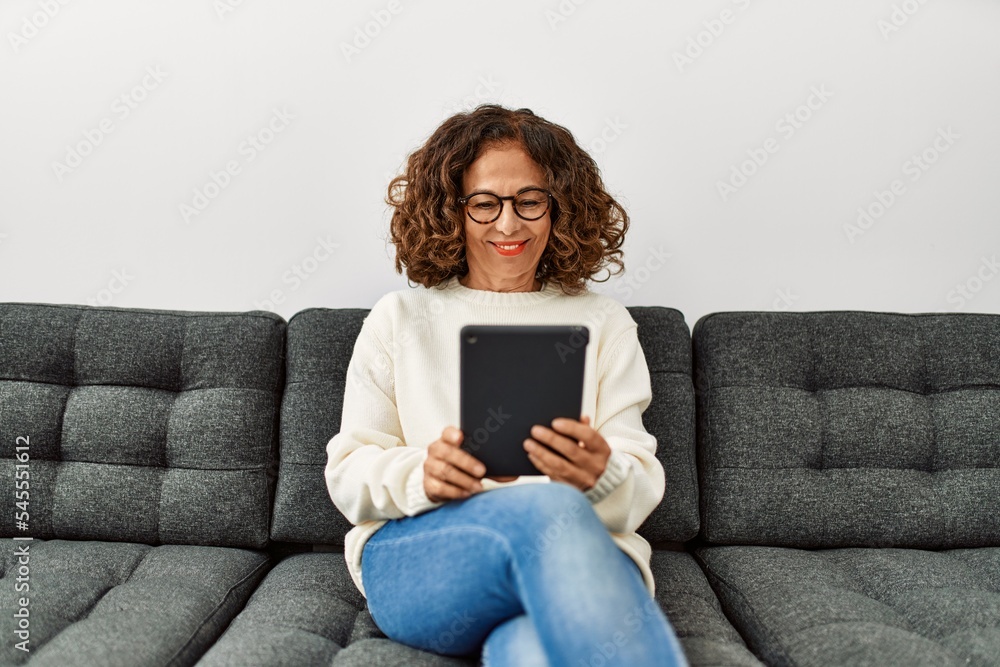Middle age hispanic woman smiling confident using touchpad at home Middle age hispanic woman smiling confident using touchpad at home