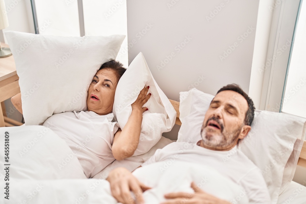Middle age man and woman couple unhappy for snoring at bedroom Middle age man and woman couple unhappy for snoring at bedroom