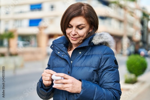 Wallpaper Mural Middle age woman smiling confident holding earphones at street Torontodigital.ca