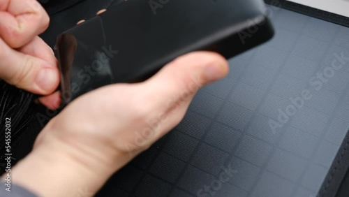 Hands plug in portable solar panel charging power bank by mutlipurpose cable, smartphone, watches, laptops. Clean energy for using in camping or at home when NO electricity