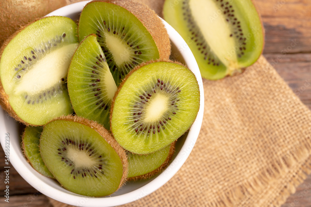 fresh green kiwis slice in the white bowl on the old wooden table fresh green kiwis slice in the white bowl on the old wooden table