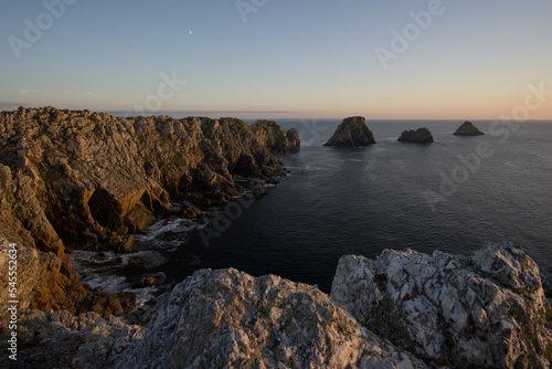 View at the coastline at Pointe de Pen-Hir at sunset with moon on the sky, Camaret-sur-Mer, Parc naturel regional Armorique, Brittany, France