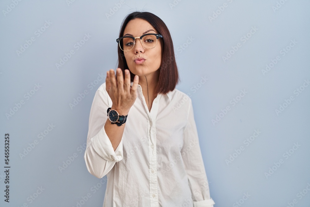 Young hispanic woman standing over white background looking at the camera blowing a kiss with hand on air being lovely and sexy. love expression. Young hispanic woman standing over white background looking at the camera blowing a kiss with hand on air being lovely and sexy. love expression.