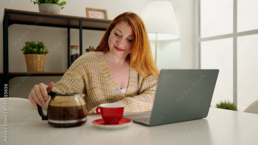 Young redhead woman using laptop drinking coffee at home Young redhead woman using laptop drinking coffee at home