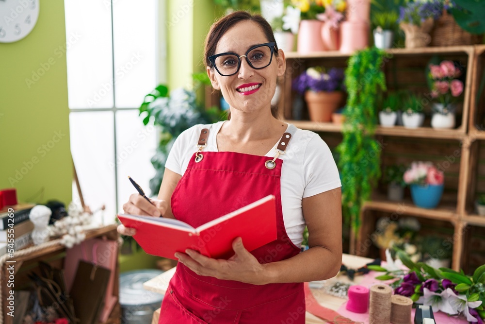 Young beautiful hispanic woman florist smiling confident writing on notebook at flower shop Young beautiful hispanic woman florist smiling confident writing on notebook at flower shop
