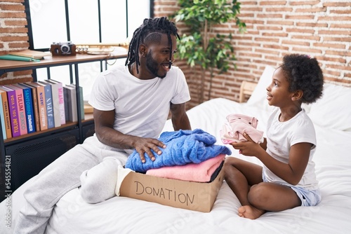 Father and daughter folding clothes to donate at bedroom photo